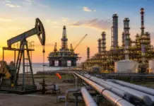 Nigeria Oil and Gas Sector Surges with Renewed Momentum Offshore oil platform complex at sunset with a pumpjack in the foreground and extensive piping nearby.