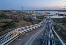 Türkiye Proposes Energy Corridor to Bolster Energy Security Industrial oil refinery with large pipelines and storage tanks by the water, ships docked at a port at dusk