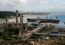 Petrobras, Pemex Sign Oil and Gas Cooperation Agreement Coastal oil refinery with interconnected pipelines, storage tanks, and tall processing towers near a docked cargo ship by the water