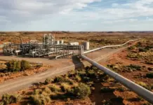 Santos Signs Gas Supply Agreement with South Australia Industrial oil/gas processing facility with pipelines in a desert landscape and a long road stretching to the horizon.