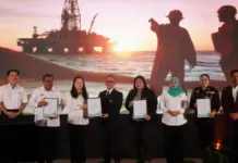 Sabah, Petronas Launch Digital Tools to Upgrade Workforce Eight people stand on a stage holding certificates during an award ceremony, with a sunset offshore oil rig backdrop behind them.