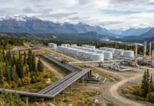 Enbridge to Buy Tallgrass Energy Assets in USD 2.55B Deal Large industrial facility with numerous white storage tanks and interconnected pipelines in a forested mountain valley.